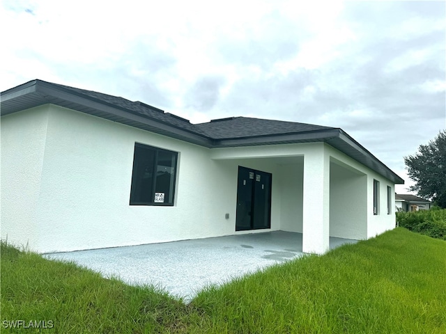 back of property with a lawn and a patio