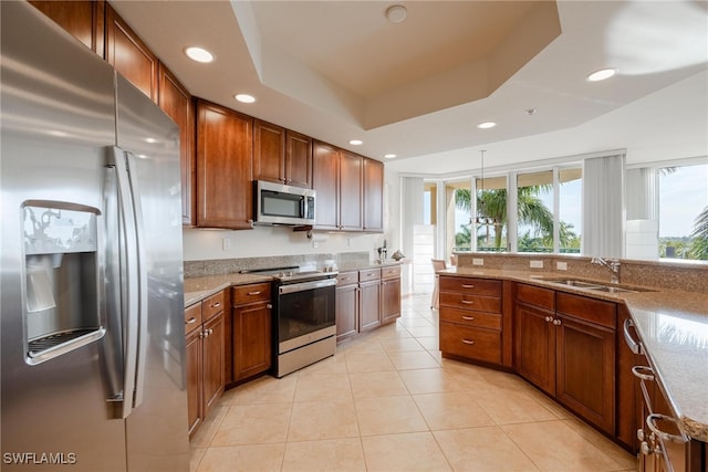 kitchen with appliances with stainless steel finishes, light stone countertops, light tile patterned flooring, and a raised ceiling