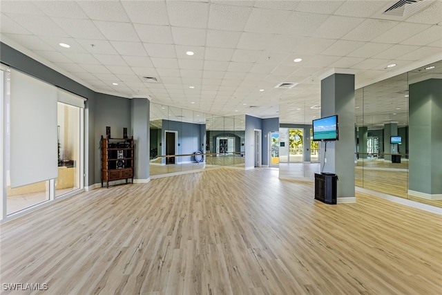 workout area featuring a drop ceiling and light hardwood / wood-style flooring