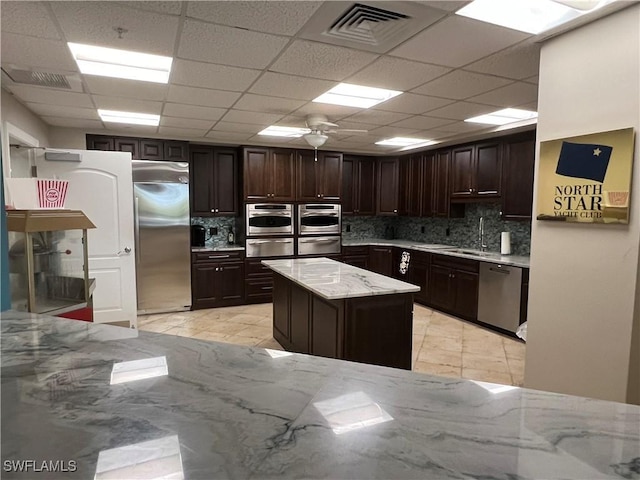 kitchen featuring stainless steel appliances, dark brown cabinets, and backsplash