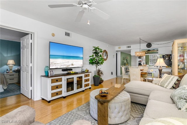 living room featuring light hardwood / wood-style flooring and ceiling fan with notable chandelier