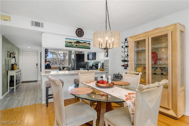 dining space featuring light hardwood / wood-style floors and a notable chandelier