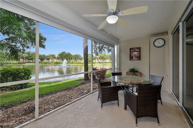 sunroom / solarium featuring ceiling fan and a water view