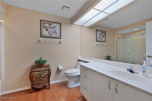 bathroom with toilet, an enclosed shower, a skylight, vanity, and hardwood / wood-style flooring