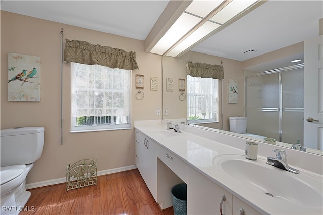 bathroom with hardwood / wood-style flooring, vanity, a shower with shower door, and toilet