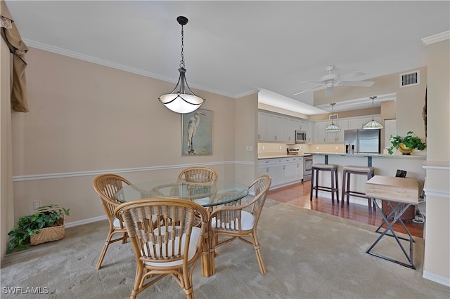 dining area with crown molding, ceiling fan, and light carpet