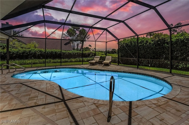 pool at dusk with a lanai and a patio area