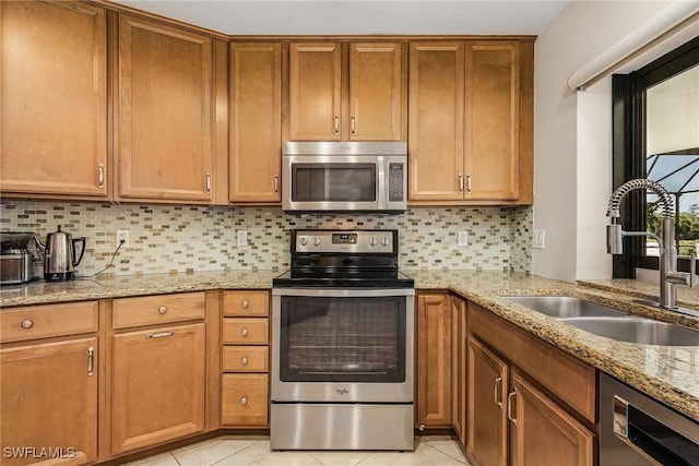 kitchen featuring sink, tasteful backsplash, light tile patterned floors, appliances with stainless steel finishes, and light stone countertops