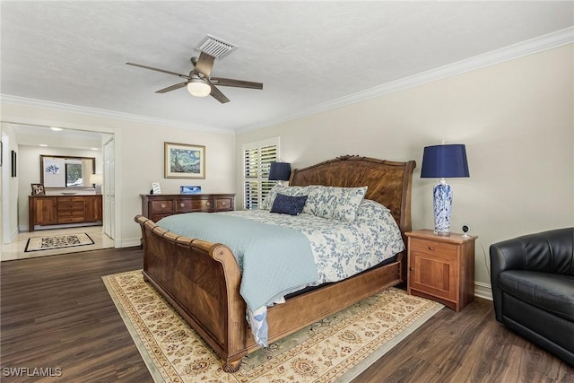 bedroom with ornamental molding, dark wood-type flooring, ensuite bathroom, and ceiling fan