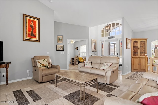 tiled living room with ceiling fan with notable chandelier and high vaulted ceiling