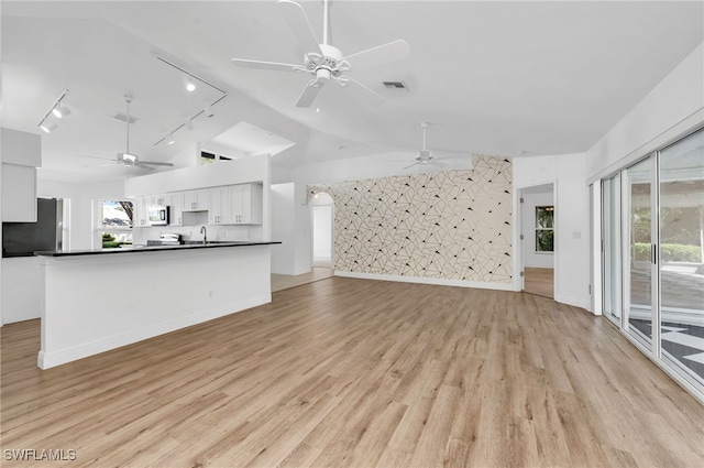 unfurnished living room featuring lofted ceiling, light hardwood / wood-style flooring, and track lighting