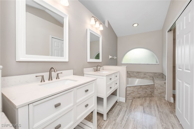 bathroom featuring tiled tub, hardwood / wood-style flooring, and vanity