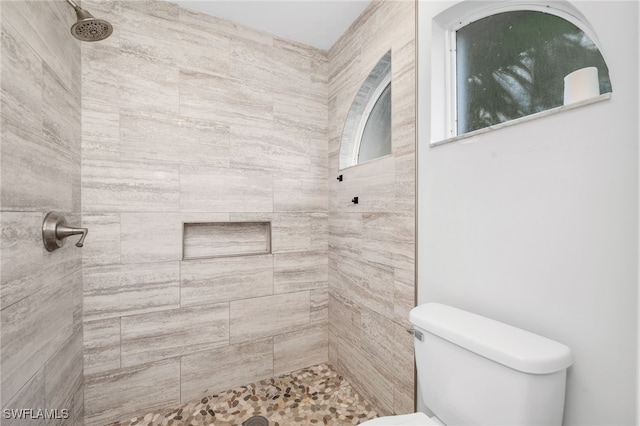 bathroom featuring a tile shower and toilet