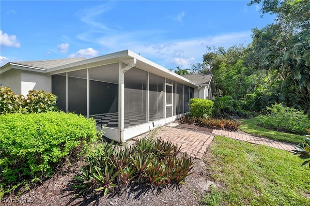 rear view of house featuring a sunroom and a lawn