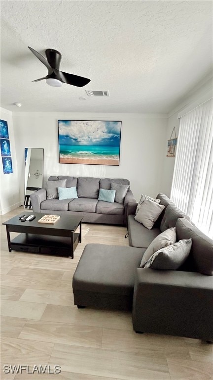 living room featuring ceiling fan and a textured ceiling