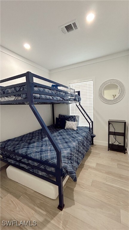 bedroom with wood-type flooring and crown molding