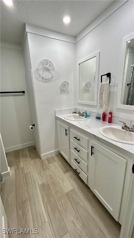 bathroom featuring wood-type flooring, vanity, and a textured ceiling