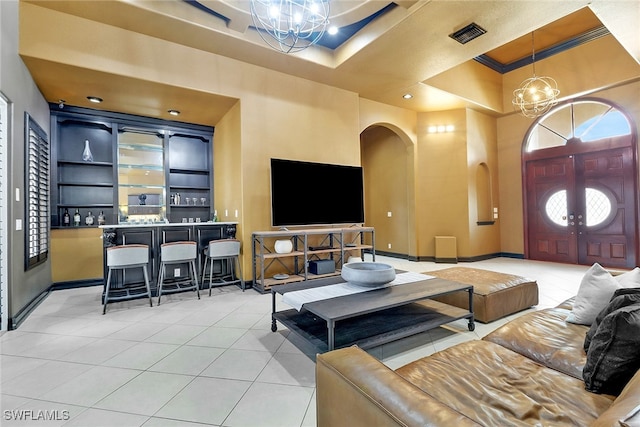 living room featuring a tray ceiling, a towering ceiling, light tile patterned floors, and a chandelier