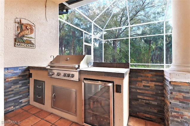 view of patio with area for grilling, glass enclosure, and an outdoor kitchen