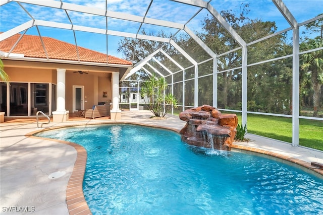 view of swimming pool with pool water feature, ceiling fan, a patio, and a lanai