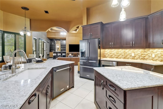 kitchen with light stone countertops, sink, appliances with stainless steel finishes, and dark brown cabinetry