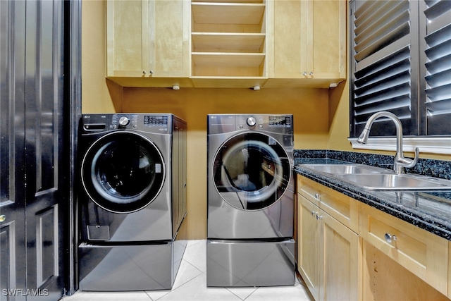 clothes washing area featuring sink, light tile patterned flooring, cabinets, and washing machine and clothes dryer