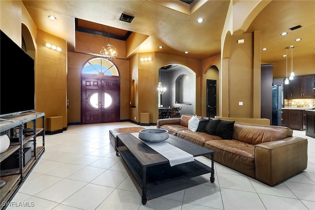 tiled living room featuring a towering ceiling, ornamental molding, and an inviting chandelier