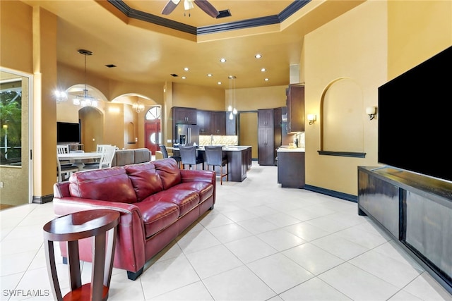 tiled living room with crown molding, ceiling fan, and a raised ceiling