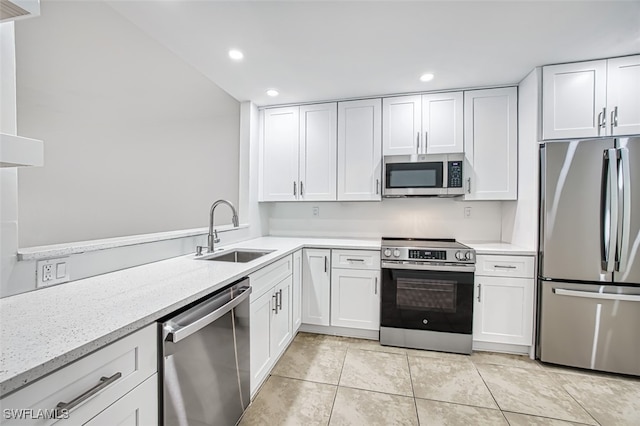 kitchen featuring appliances with stainless steel finishes, light stone countertops, sink, and white cabinets