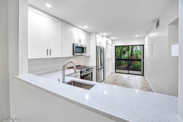 kitchen with light stone counters, sink, light tile patterned floors, white cabinetry, and stainless steel appliances