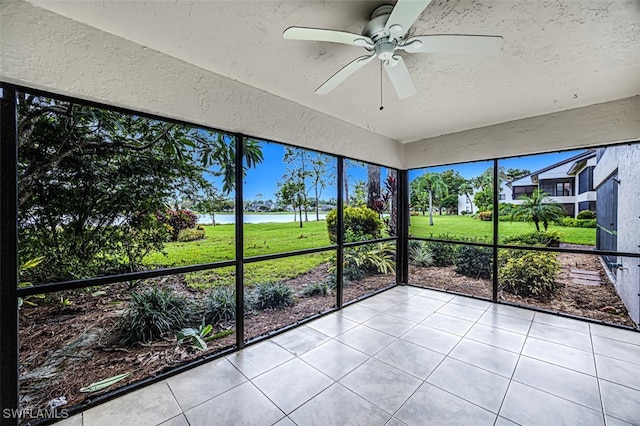 unfurnished sunroom with ceiling fan and a water view