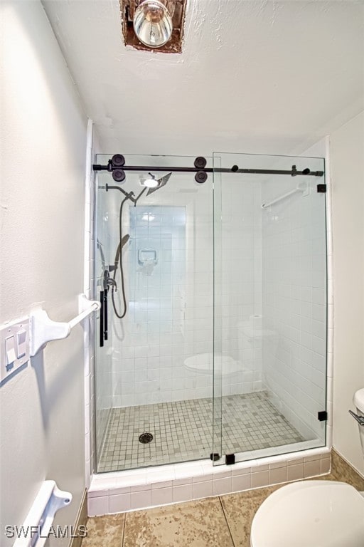 bathroom featuring tile patterned floors, toilet, and walk in shower