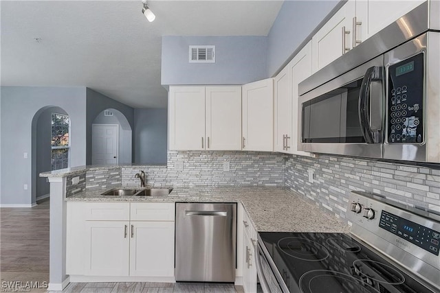 kitchen featuring stainless steel appliances, light hardwood / wood-style floors, light stone counters, and white cabinetry