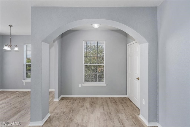 empty room with an inviting chandelier and light hardwood / wood-style flooring