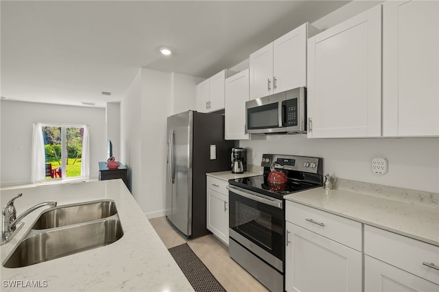 kitchen featuring light stone countertops, appliances with stainless steel finishes, sink, and white cabinetry