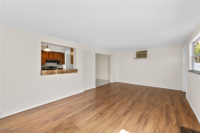 unfurnished living room featuring an AC wall unit and hardwood / wood-style floors