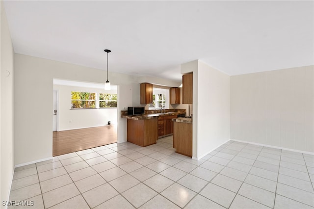 1235 Rordon Ave, Naples, FL 34103 - kitchen featuring open floor plan, brown cabinetry, stainless steel microwave, dark countertops, and light tile patterned floors