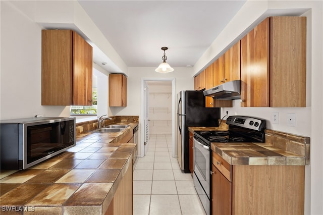 kitchen with stainless steel appliances, hanging light fixtures, sink, and light tile patterned flooring