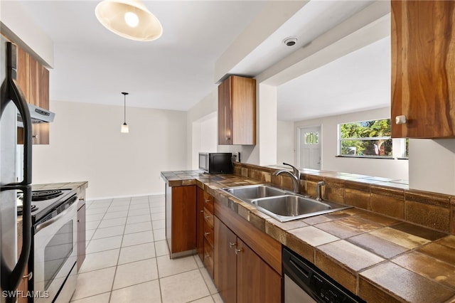 kitchen featuring tile countertops, sink, appliances with stainless steel finishes, light tile patterned floors, and hanging light fixtures