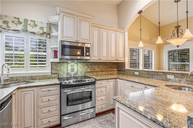 kitchen featuring light stone counters, decorative light fixtures, stainless steel appliances, and sink