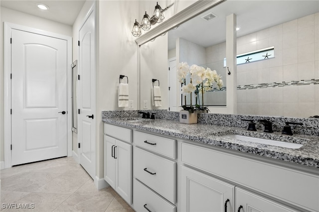 bathroom with tile patterned flooring, vanity, and a tile shower