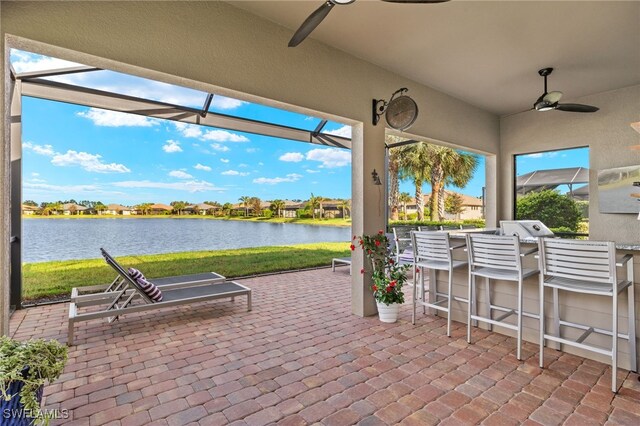 view of patio featuring a bar, a water view, and ceiling fan