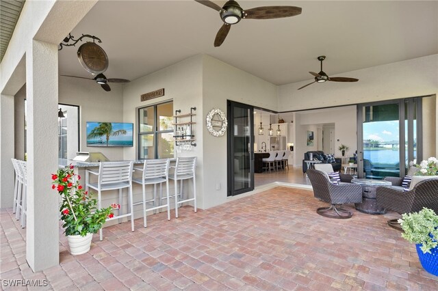 view of patio featuring ceiling fan, an outdoor living space, and exterior bar