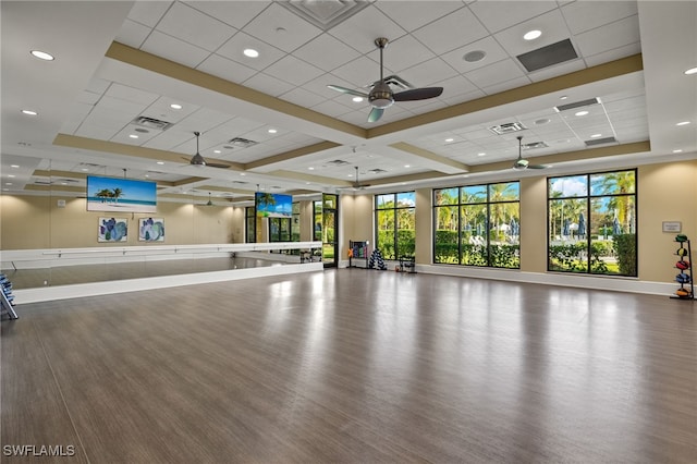 exercise area featuring a paneled ceiling, ceiling fan, and a healthy amount of sunlight