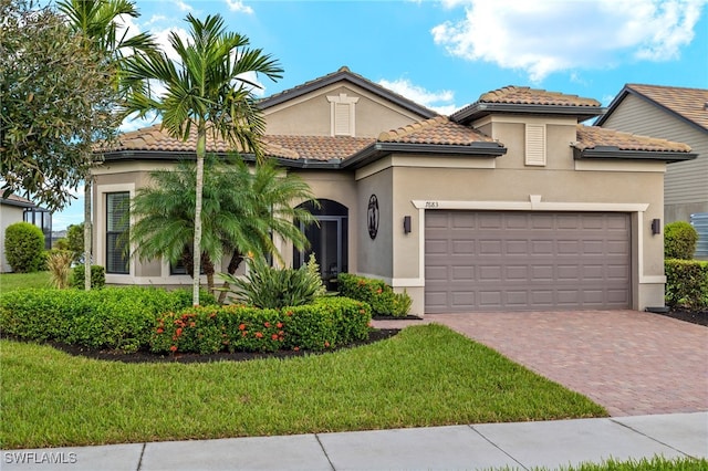 mediterranean / spanish-style house with a garage and a front lawn