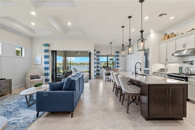 tiled living room with ceiling fan, sink, beamed ceiling, and coffered ceiling