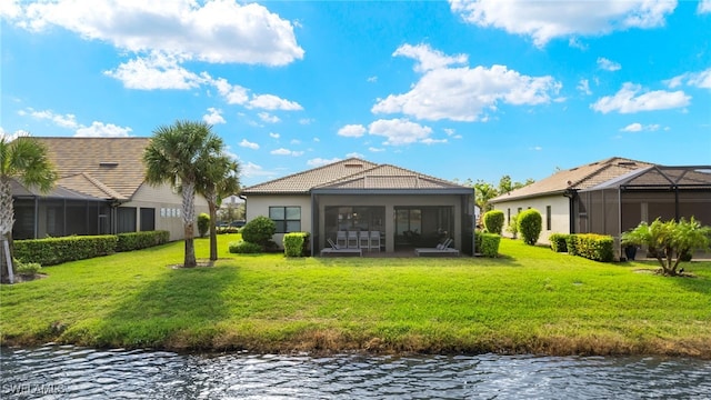 back of house featuring a lawn, a sunroom, and a water view