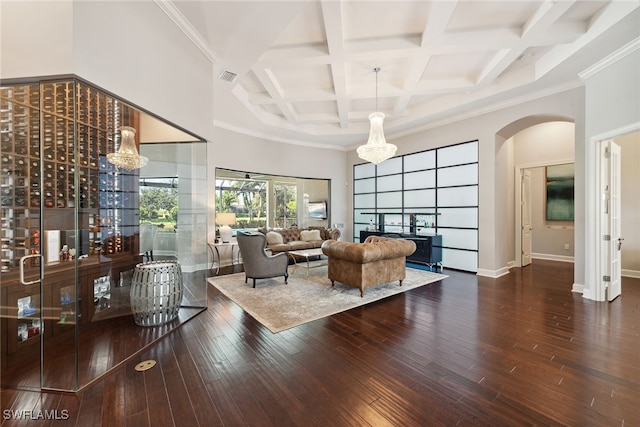 living room with coffered ceiling, beamed ceiling, dark wood-type flooring, crown molding, and a notable chandelier