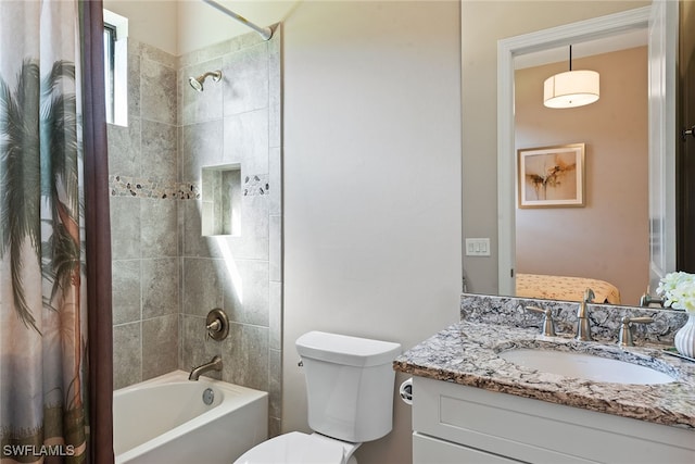 full bathroom featuring tiled shower / bath, vanity, and toilet