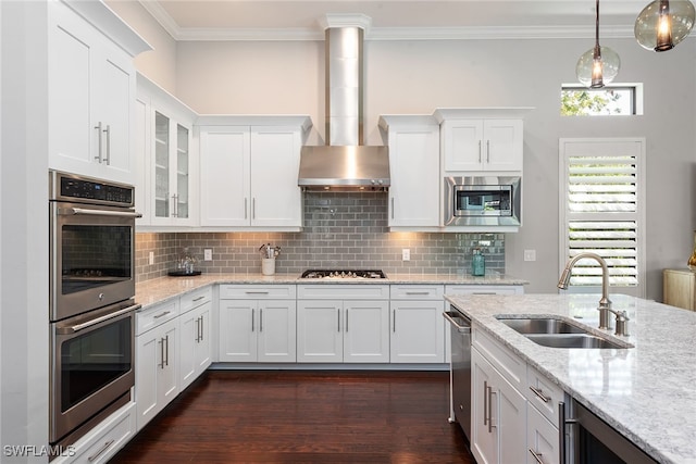 kitchen featuring wall chimney exhaust hood, sink, appliances with stainless steel finishes, and white cabinetry